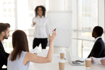 Rear view at woman employee student raising hand at business class, training, diverse group meeting...