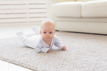 Childhood, infant and people concept - small baby lying on the floor