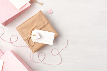 Creative image of gift bag and box with empty tag, heart and christmas decoration in pink pastel colors. Christmas, Saint Valentine, birthday shopping, sales and presents