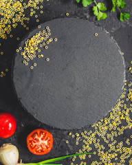 pasta anelli and slate plate on a dark table (set of ingredients). Vegan food.  (dark background). top view. copy space