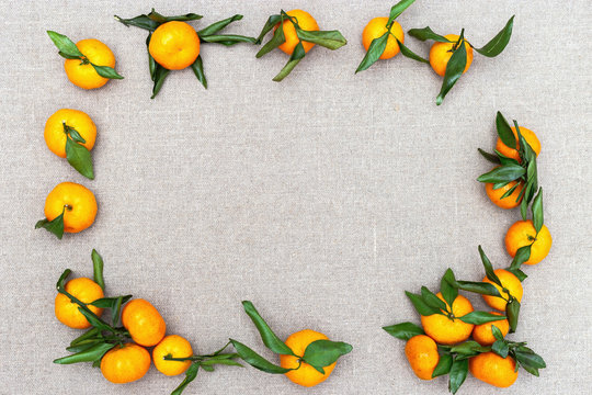 Frame from tangerines on sackcloth background. Tangerines with green leaves on background from  sackcloth.