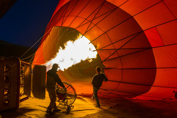 Silhouette eines Mannes mit nächtlichen Heißluftballons, die sich aufblasen