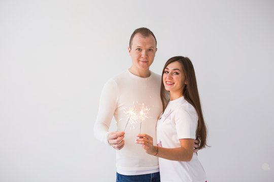 Valentine's Day concept - Young happy smiling cheerful attractive couple celebrating with sparklers on white background with copy space