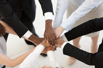 Diverse business people group put hands together in stack pile at training as concept of sales team...
