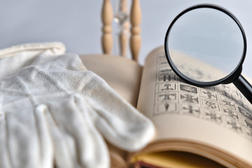 White glove, magnifying glass and hourglass with old book