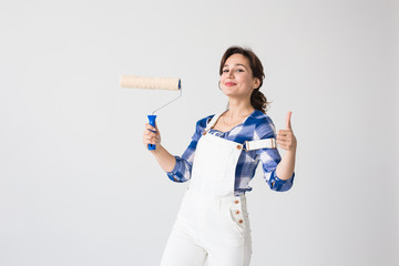 Repair, renovation, new home and people concept - Beautiful woman paints the wall during...