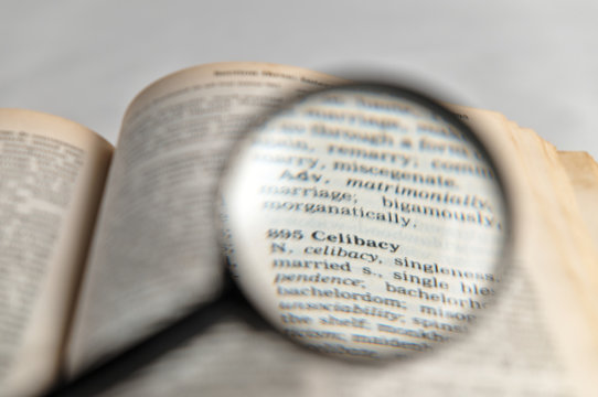 Celibacy word magnified on old book