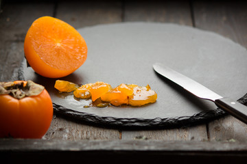 persimmon ripe orange fruit on a dark rustic background texture and copy space