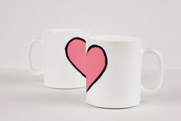 Pink heart and two cups on white background. Valentine's day, love, couple, wedding concept