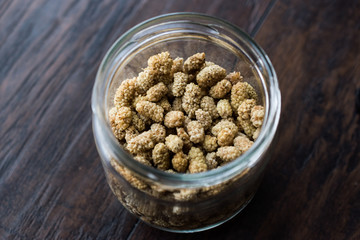 Jar of Dried Mulberries on Dark Wooden Surface.