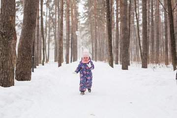 Fototapeta na wymiar Child running in snowy forest. Toddler kid playing outdoors. Kid play in snowy park.