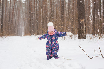 Fototapeta na wymiar Children and nature concept - Adorable baby girl walking in winter park