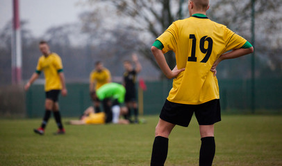 Young football player on the field during a football match in a yellow T-shirt with the number...