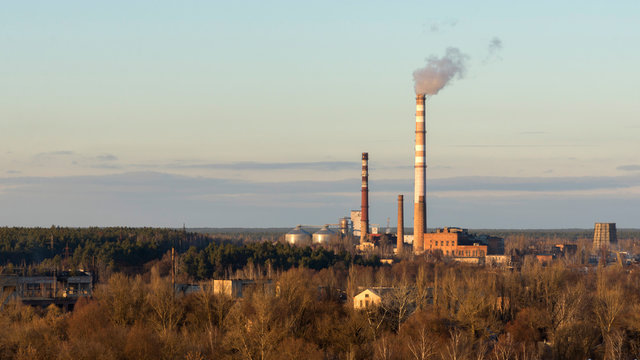 Evening View Of The City, The Pipes Of The Plant With Smoke Coming Out Of Them