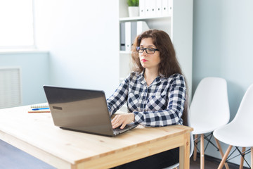 Technology, business and people concept - Serious woman in glasses working at the computer in office