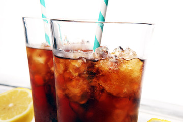 Softdrink with ice cubes, lemon and straw in glass
