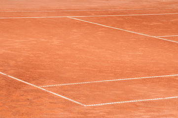Part of empty used red clay tennis court playground surface with white lines closeup
