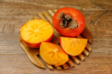 Ripe Persimmon kaki fruit or japanese apple. Close-up on wooden table, low light.