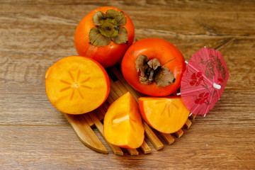 Ripe Persimmon kaki fruit or japanese apple. Close-up on wooden table, low light.