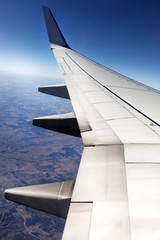 In flight airplane wing with rugged Texas terrain below.