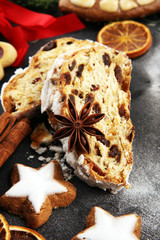 Traditional European Christmas pastry, fragrant home baked stollen, with spices and dried fruit. Sliced on rustic table with xmas tree branches and decorations