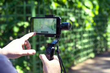 Close up male traveler  records video and photo on smartphone using image stabilizer.