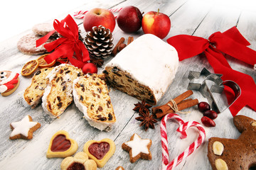Traditional European Christmas pastry, fragrant home baked stollen, with spices and dried fruit. Sliced on rustic table with xmas tree branches and decorations