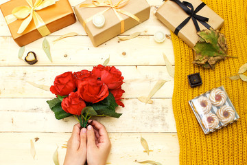 autumn and holiday concept: close up of hand woman holding roses bouquet of flowers and boxes...