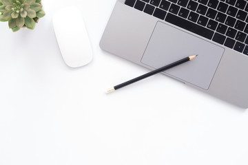 Creative flat lay photo of workspace desk. Top view office desk with laptop, glasses, pencil and plant on white color background. Top view with copy space, flat lay photography.