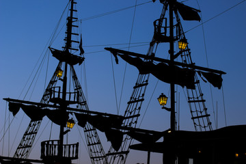 romantic and atmospheric sea shot of vintage old pirate medieval ship silhouette shapes of mast and...