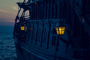 yellow illumination from soft focus vintage lamp in over board of wooden old pirate ship on sea...