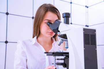 Young woman technician is examining a histological sample, a biopsy in the laboratory of cancer...