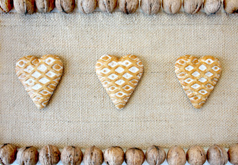 Gingerbread hearts on jute fabric surrounded by walnuts, Christmas table decorations