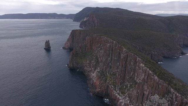 Wide angle drone shot of remote coastline in Tasmania with cliffs and rocks out of the water
