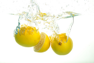 Three lemons spash in water on white background