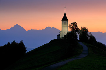 Jamnik church sunrise, landscape in Slovenia, nature in Europe.  Foggy Triglav Alps with forest,...