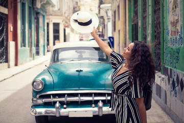 Young beautiful black woman with a typical cuban hat standing in the old streets of Havana Cuba in...