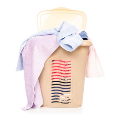 Plastic laundry basket with clothing and pile towels on white background isolation