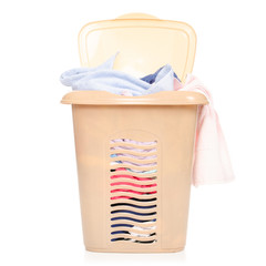 Plastic laundry basket with clothing and pile towels on white background isolation