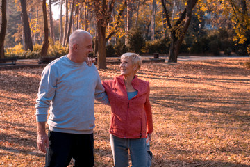 Senior man and woman exercise together in autumn park
