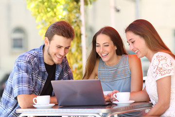 Three friends watching media content on laptop in a bar