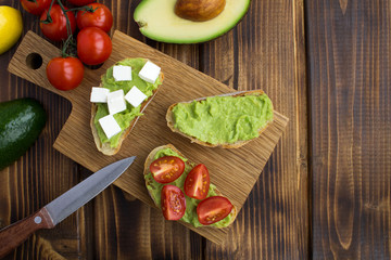 Vegetarian sandwiches with avocado,cherry and soft cheese on the brown  wooden background.Top view.Copy space.
