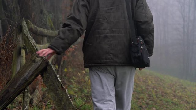 Man touches old wooden fence and goes into dense fog - (4K)
