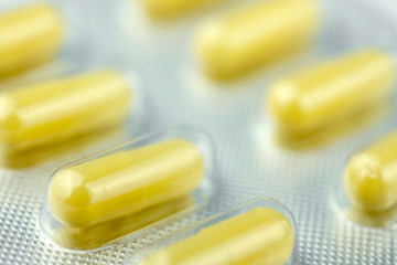 Packaging with yellow and white pills for treatment. Close up.