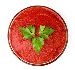 Tomato paste in a glass plate with parsley leaves. The view from the top.