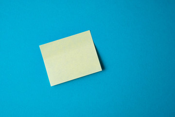 Yellow paper sticker on blue background. Close up.