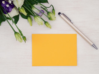 Envelope, pen and roses flowers on white wooden table. Flat lay. Top view.