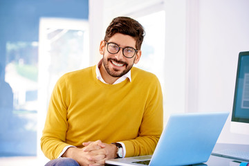 Confident businessman using his notebook while sitting at office desk