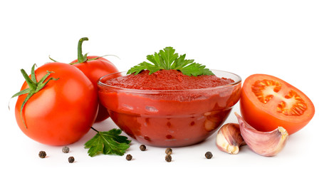 Tomato paste in a plate with parsley leaves and tomatoes on a white background. Isolated.