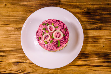 White plate with russian traditional new year salad herring under fur coat on wooden table. Top view